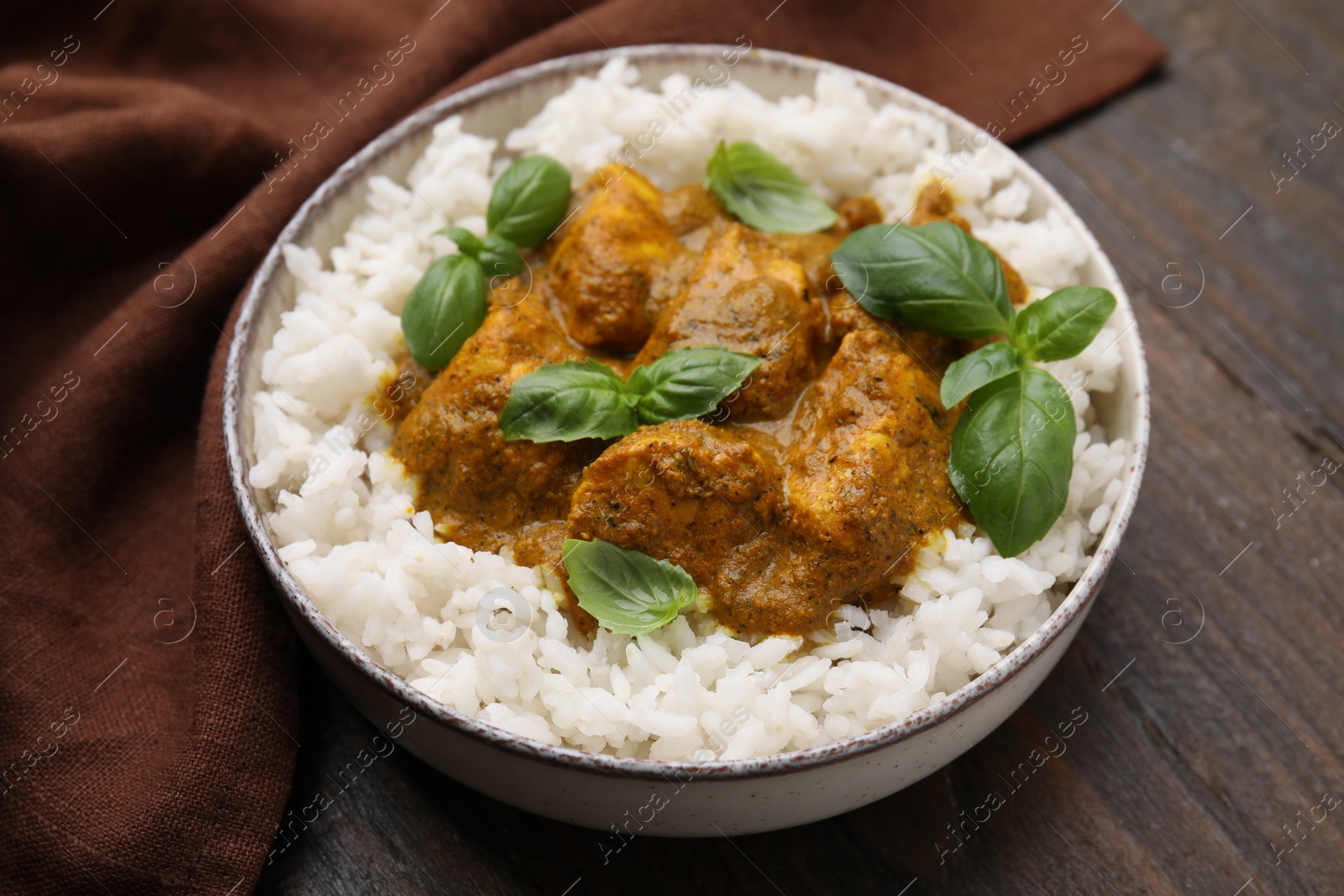 Photo of Delicious rice and chicken with curry sauce served on wooden table, closeup