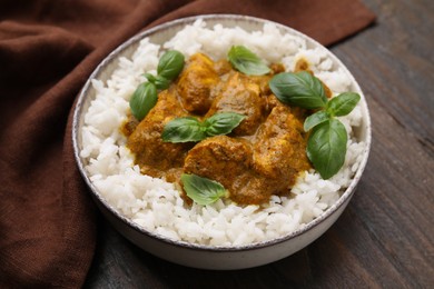 Delicious rice and chicken with curry sauce served on wooden table, closeup