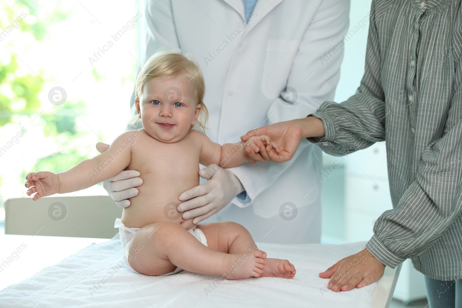 Photo of Mother with her baby visiting pediatrician in hospital. Health growth