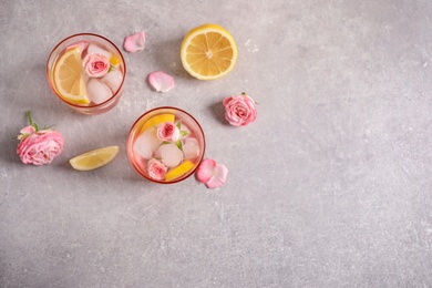 Photo of Tasty refreshing lemon drink with roses on light grey table, flat lay. Space for text