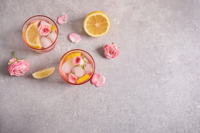 Tasty refreshing lemon drink with roses on light grey table, flat lay. Space for text