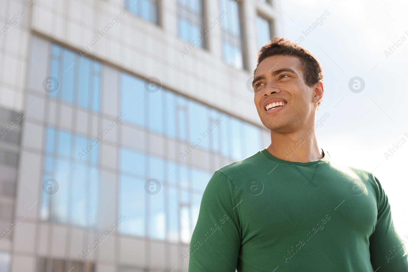 Photo of Portrait of handsome young African-American man on city street, low angle view. Space for text
