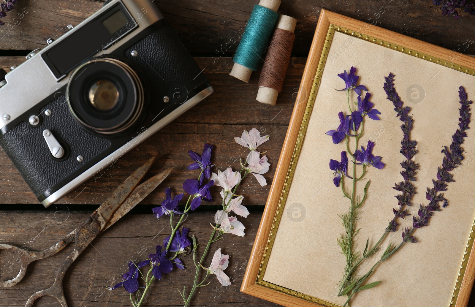 Photo of Flat lay composition with beautiful dried flowers, vintage camera and photo frame on wooden table