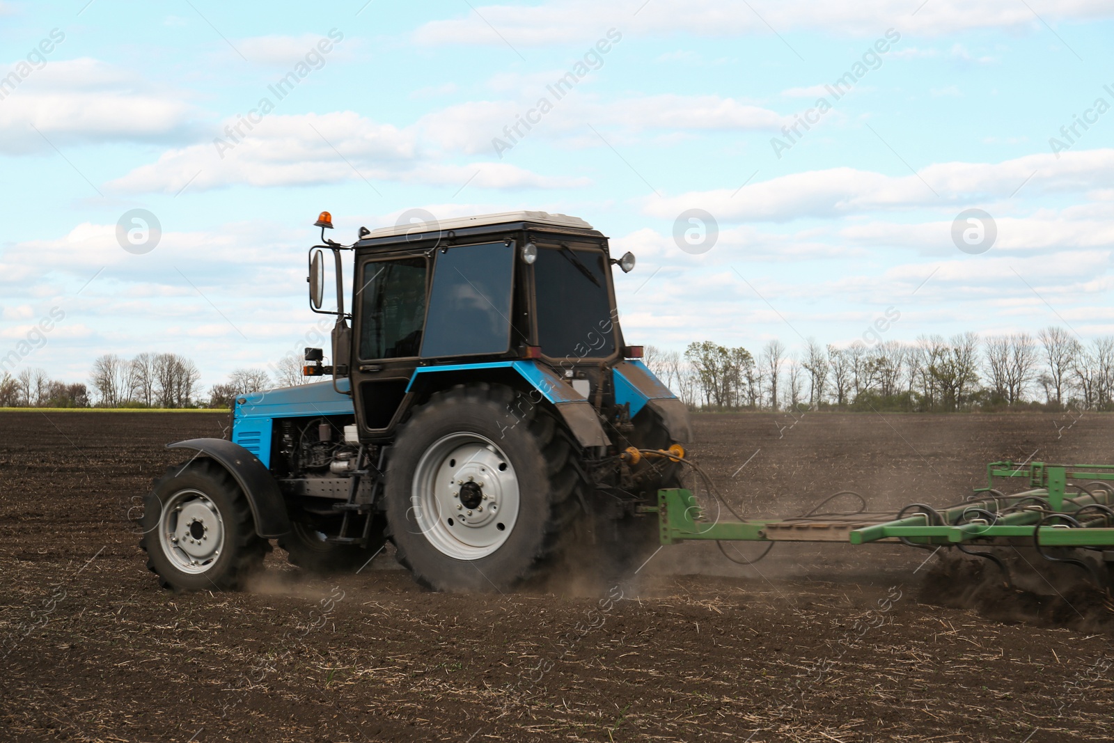 Photo of Tractor with planter cultivating field on sunny day. Agricultural industry