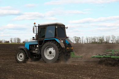 Tractor with planter cultivating field on sunny day. Agricultural industry