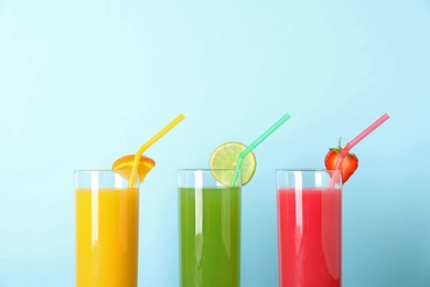 Photo of Three glasses with different juices and straws on color background