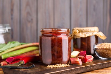Tasty rhubarb sauce and ingredients on wooden table, space for text