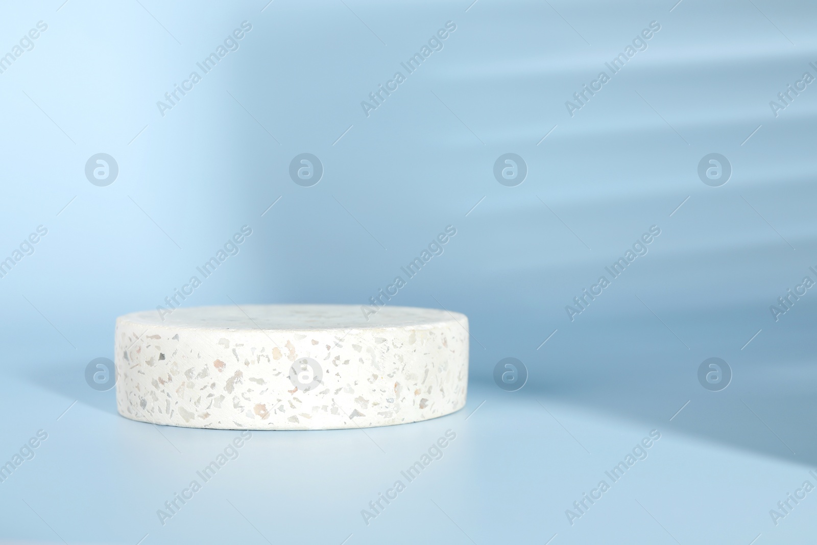 Photo of Presentation of product. Round podium and shadows on light blue background. Space for text