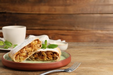 Photo of Delicious strudel with apples, nuts and raisins on wooden table. Space for text