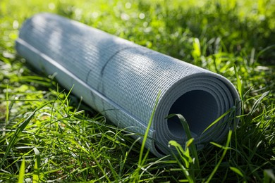 Photo of Rolled karemat or fitness mat on green grass outdoors, closeup