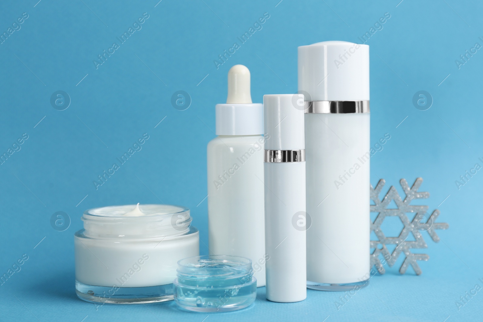 Photo of Beautiful composition with cosmetic products on light blue background. Winter care