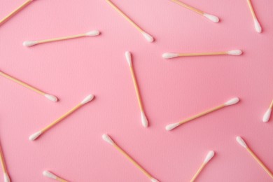 Many clean cotton buds on pink background, flat lay