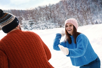 Photo of Happy couple playing snowballs outdoors. Winter vacation
