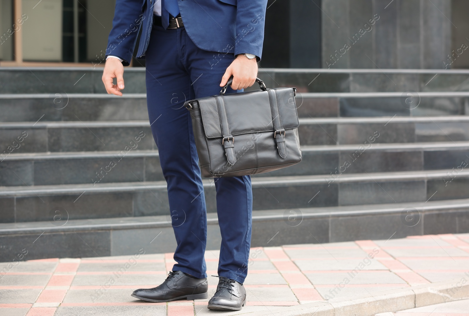 Photo of Businessman with black briefcase in hand outdoors. Space for text