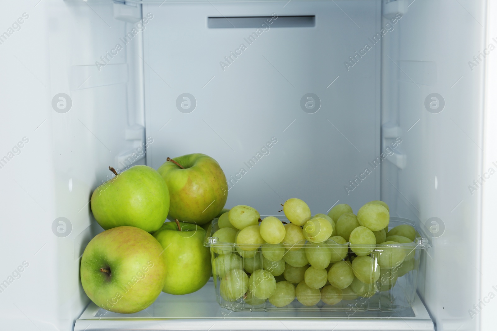 Photo of Apples and grapes on shelf in refrigerator