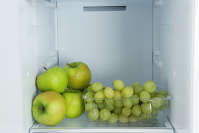 Photo of Apples and grapes on shelf in refrigerator