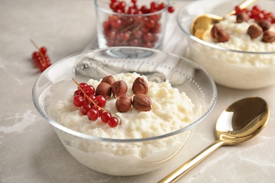 Photo of Creamy rice pudding with red currant and hazelnuts in bowls served on grey table