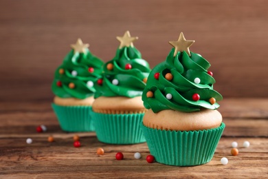 Photo of Christmas tree shaped cupcakes on wooden table