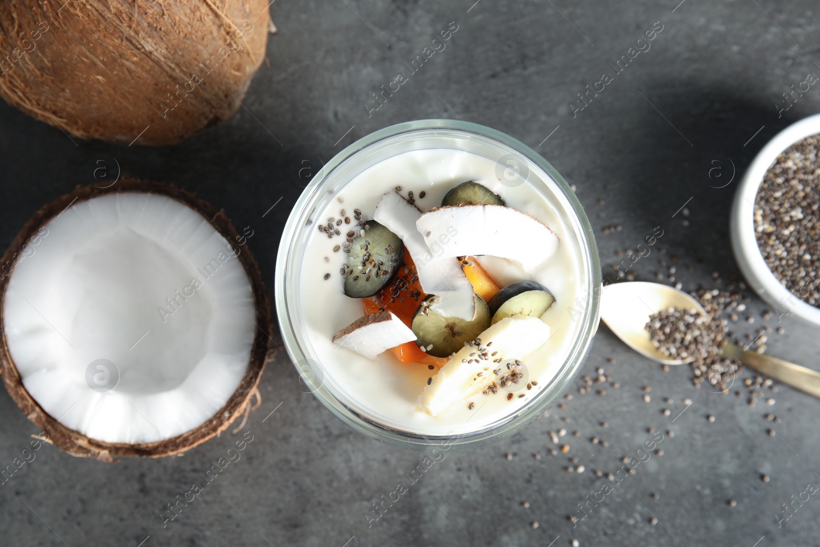 Photo of Glass of tasty chia seed pudding with coconut and ingredients on table, flat lay