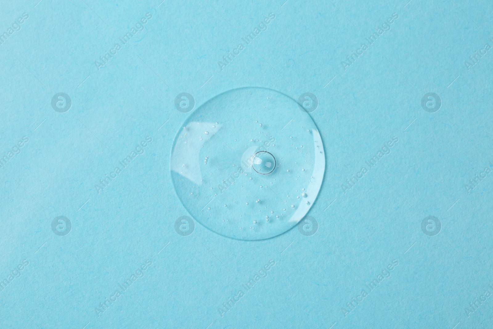 Photo of Sample of cosmetic serum on light blue background, top view
