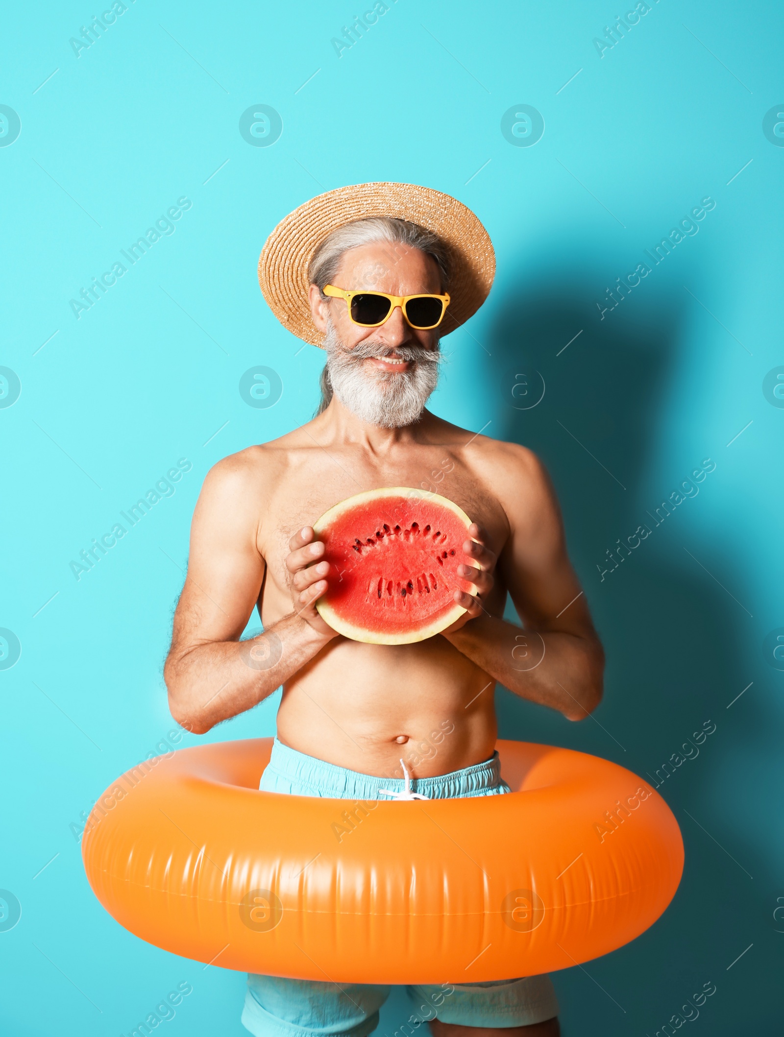 Photo of Shirtless man with inflatable ring and watermelon on color background