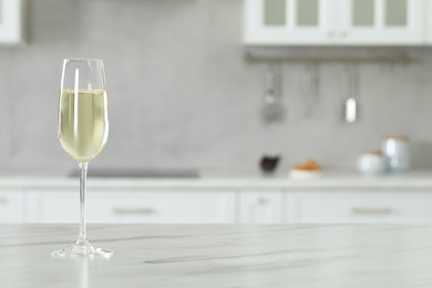 Photo of Glass of wine on white marble table in kitchen. Space for text