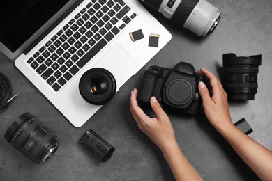 Photo of Woman with professional photographer equipment and laptop at gray table