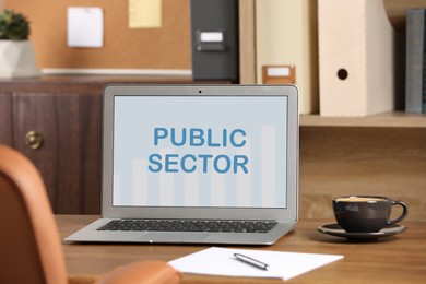 Image of Public Sector. Modern laptop and cup on table in office