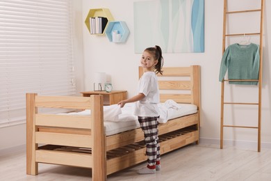 Photo of Cute girl changing bed linens in children room
