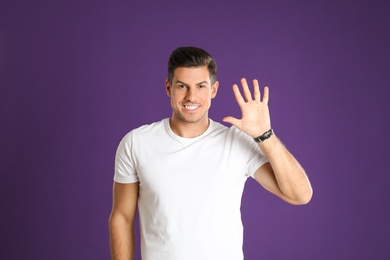 Photo of Man showing number five with his hand on purple background