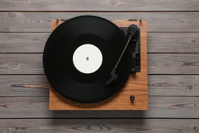 Photo of Turntable with vinyl record on wooden background, top view