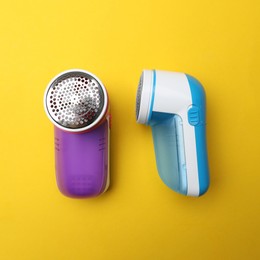 Modern fabric shavers on yellow background, flat lay