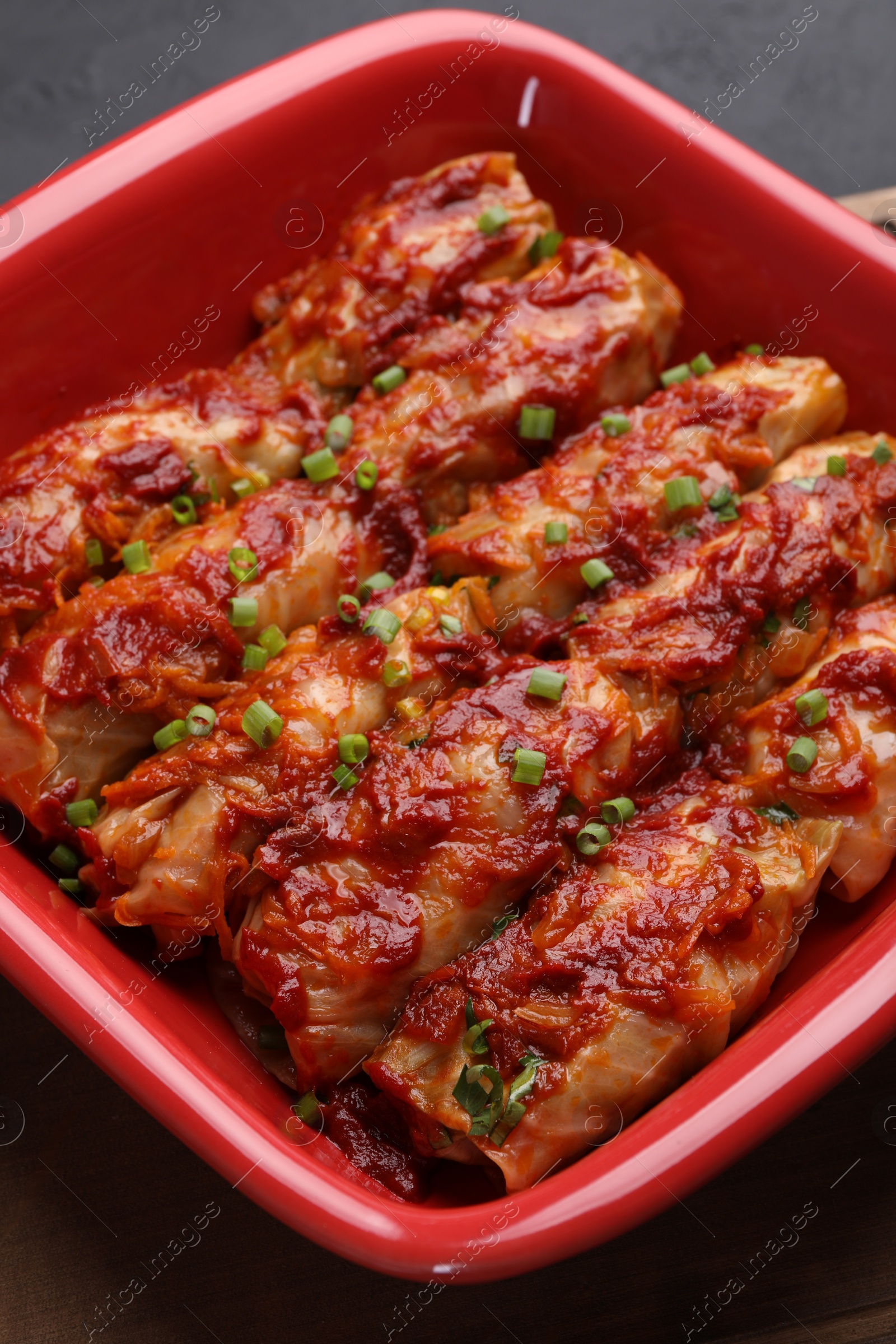 Photo of Delicious stuffed cabbage rolls cooked with homemade tomato sauce on table, closeup