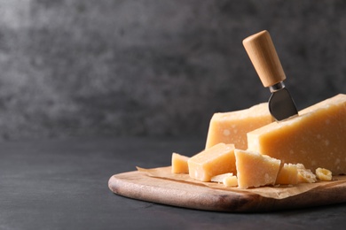 Photo of Delicious parmesan cheese with knife on black table. Space for text