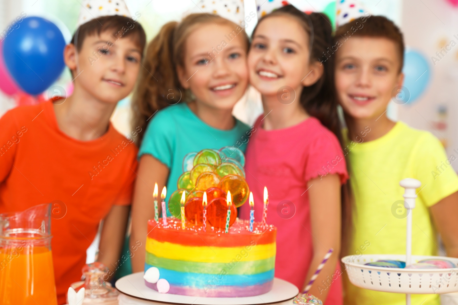 Photo of Children near cake with candles at birthday party indoors