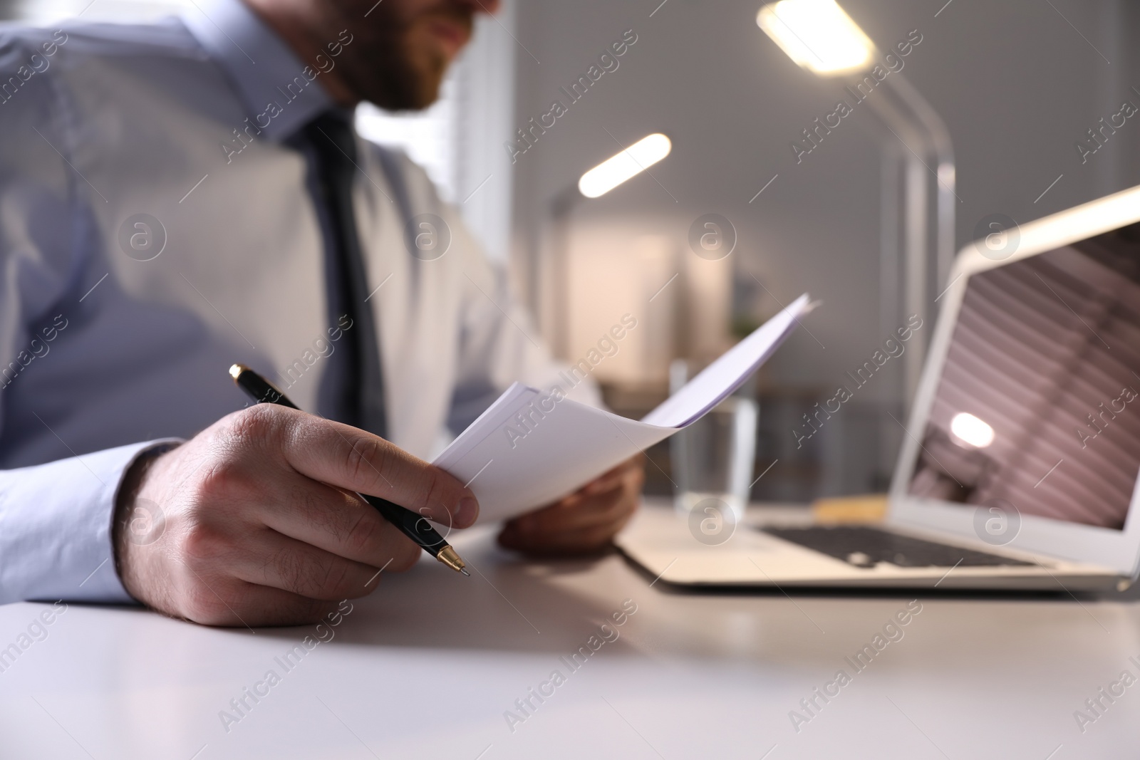 Photo of Businessman working with documents at white desk in office, closeup