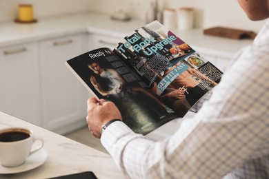 Man with coffee reading sports magazine at table in kitchen, closeup