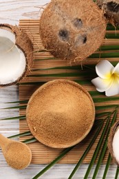 Photo of Coconut sugar, palm leaves, fruits and bamboo mat on wooden rustic table, flat lay