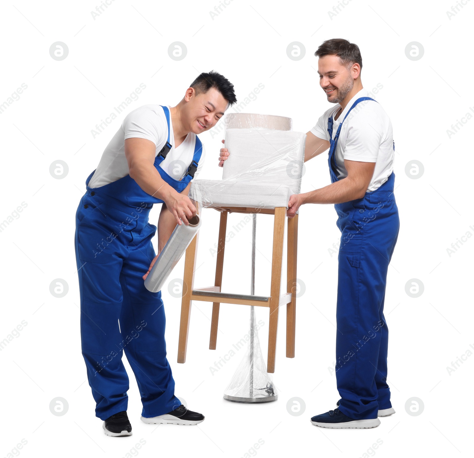 Photo of Workers wrapping chair in stretch film on white background