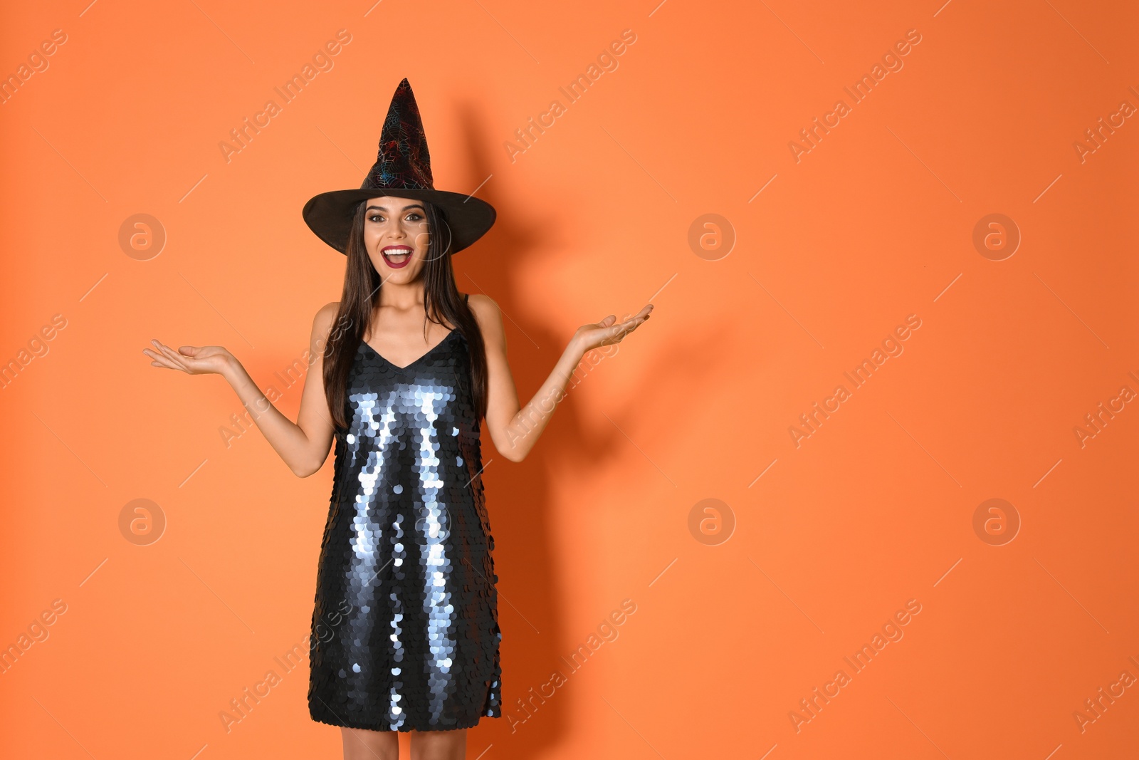 Photo of Excited woman wearing witch costume for Halloween party on yellow background, space for text