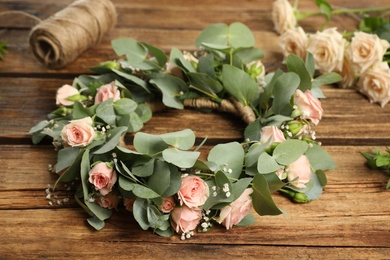 Composition with wreath made of beautiful flowers on wooden table