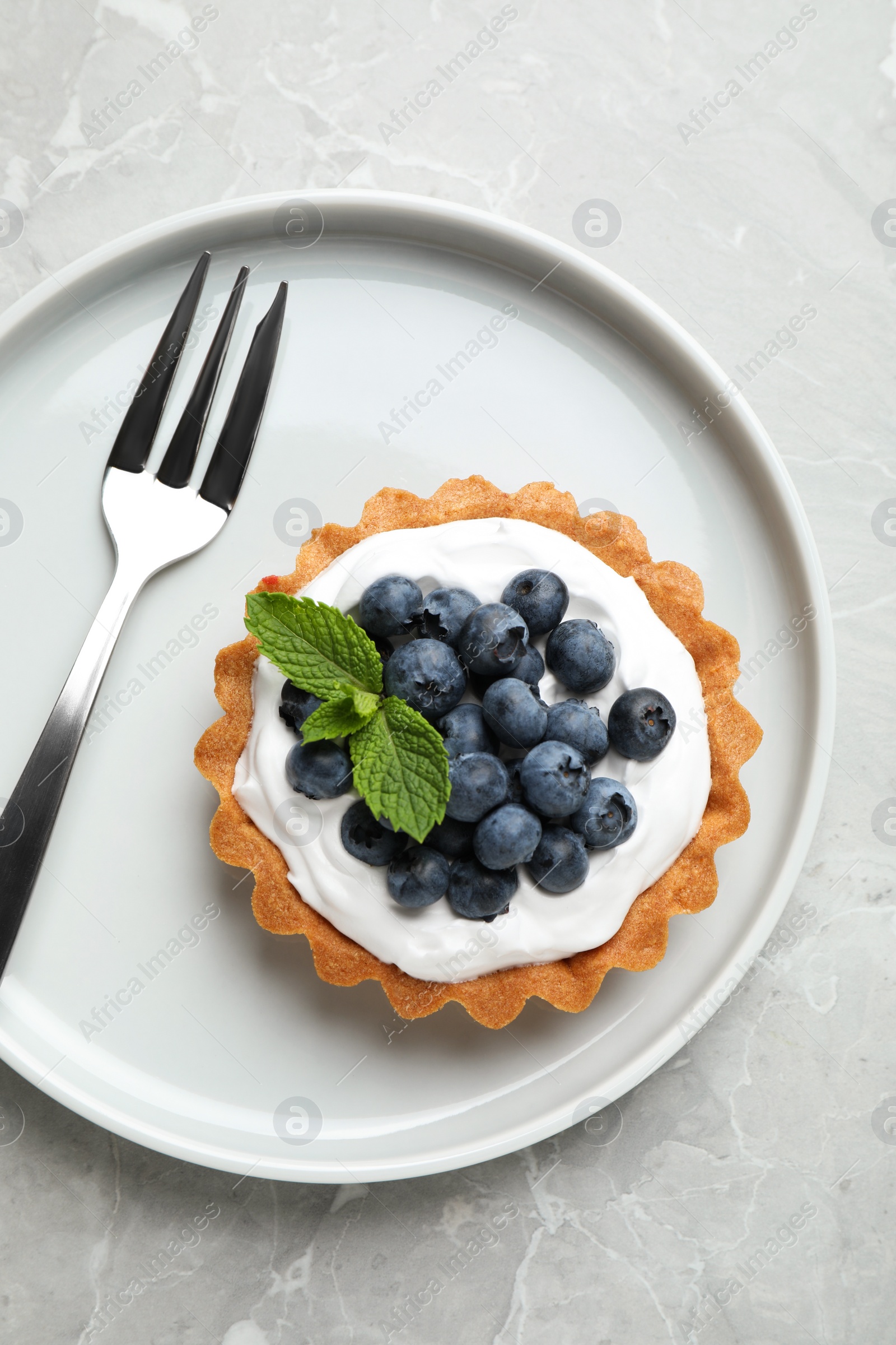 Photo of Tart with blueberries served on marble table, top view. Delicious pastries