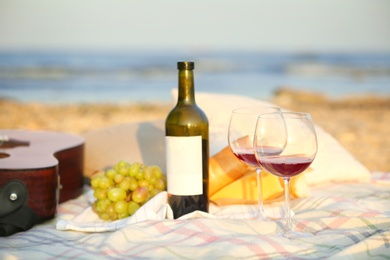 Blanket with food, wine and guitar on beach. Romantic picnic for couple