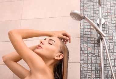 Beautiful young woman taking shower at home