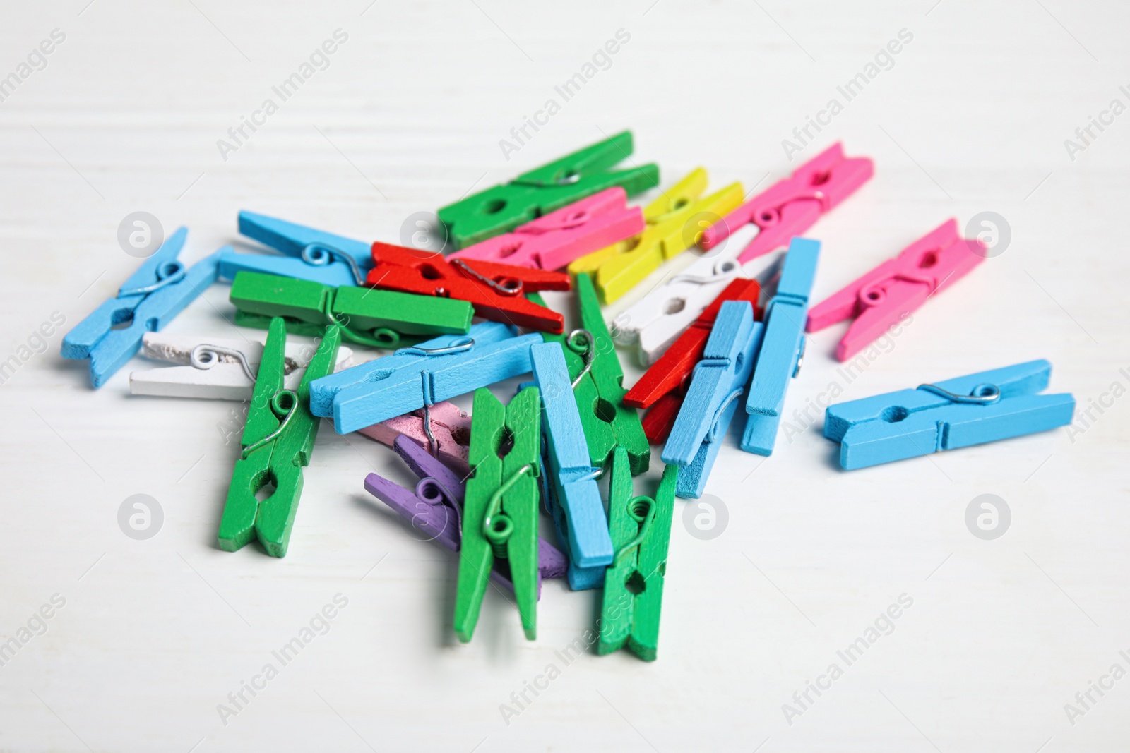 Photo of Bright colorful clothespins on white wooden table