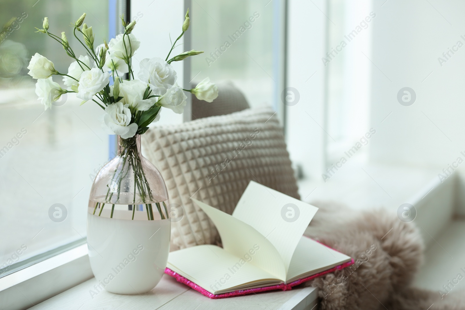 Photo of Stylish vase with fresh flowers and book on window sill