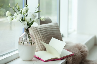 Stylish vase with fresh flowers and book on window sill