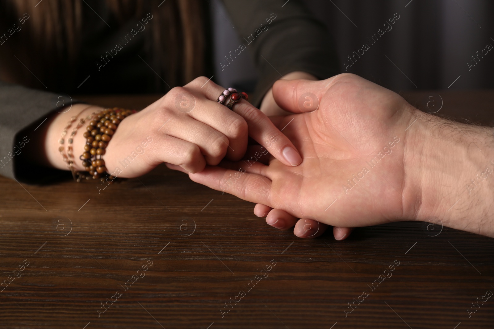 Photo of Chiromancer reading lines on man's palm at table, closeup