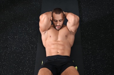 Photo of Strong man doing crunches on mat in gym