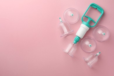 Photo of Plastic cups and hand pump on pink background, flat lay with space for text. Cupping therapy